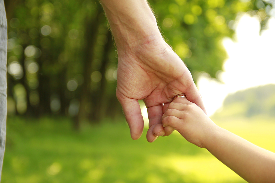 daycare worker holds child's hand